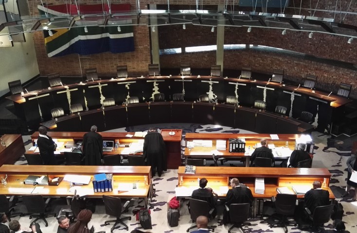 Constitutional Court Pics Livanos MDS 3 - Municipal Debt Specialist Council chamber with a circular, tiered desk and officials working at laptops and papers.",